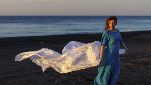 Portrait of woman standing at beach against sky