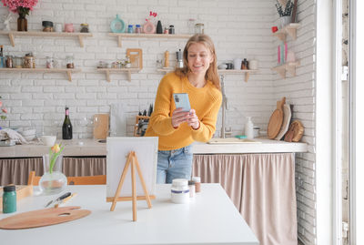 Portrait of smiling young woman standing in kitchen