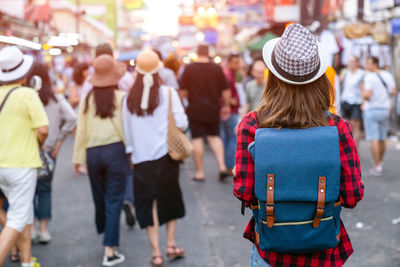 Rear view of people walking on street in city