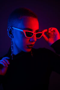 Close-up of woman wearing sunglasses against black background