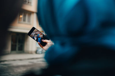 Cropped image of woman taking selfie with friend in city