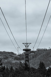 Low angle view of electricity pylon on field against sky