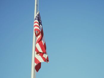 Low angle view of american flag against clear blue sky