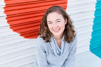 Portrait of smiling woman sitting against shutter