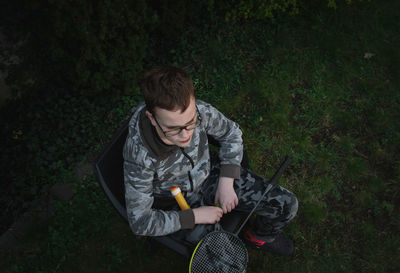 High angle view of young man holding camera on field