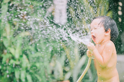 Cute girl playing with water pipe outdoors