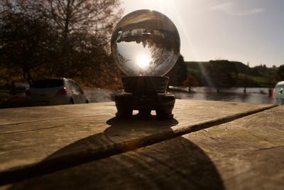 Close-up of crystal ball on table against trees during sunset