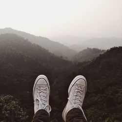 Low section of person on mountain against sky