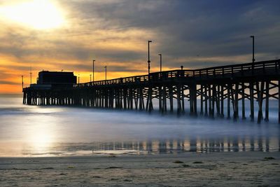 Pier over sea against sky during sunset