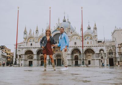 Young couple standing against cathedral in city