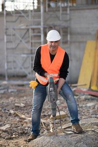 Worker drilling with jackhammer at construction site