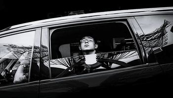 LOW ANGLE VIEW OF WOMAN WITH CAR ON MIRROR