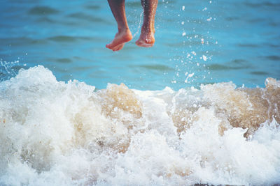 Low section of person jumping over sea