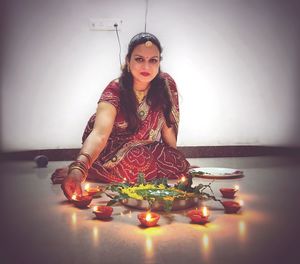 Portrait of young woman sitting in illuminated lamp