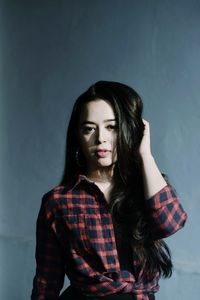 Portrait of beautiful young woman against wall