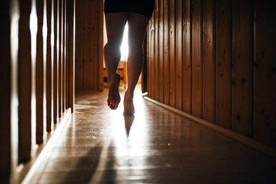 Low section of woman standing on illuminated corridor