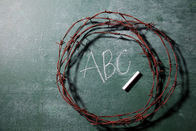 Close-up of rusty barbed wire with chalk on blackboard