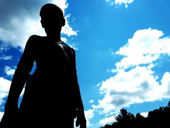 Rear view of silhouette man standing against blue sky