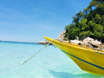 Fishing boat moored in sea against blue sky