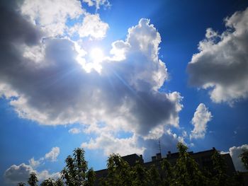 Low angle view of sunlight streaming through clouds