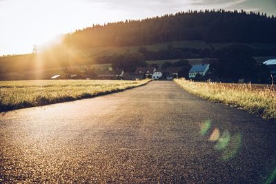 Road amidst trees on field against sky