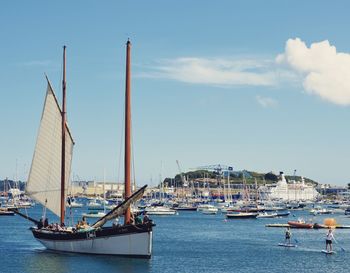 Sailboats moored at harbor against sky