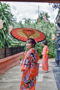 Woman holding umbrella standing during rainy season