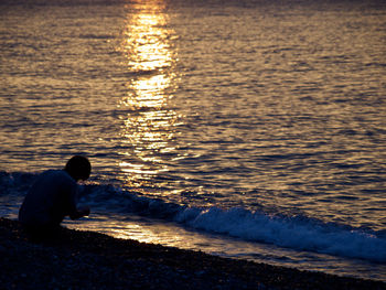 Side view of man on beach against sky during sunset