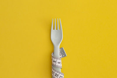High angle view of fork on yellow background