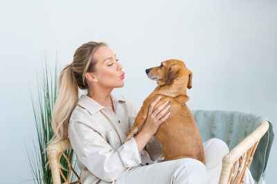 A young beautiful woman in casual clothes hugs and pets her beloved dog sitting