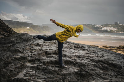Woman on rock by sea against sky