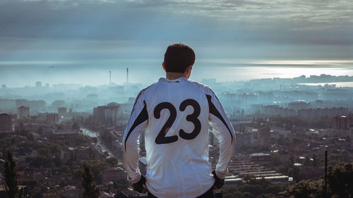 Rear view of wearing number 23 t-shirt sitting against cityscape