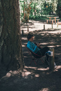 Man sitting on bench by tree