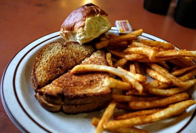 Close-up of grilled cheese sandwich with french fried and bread served on table