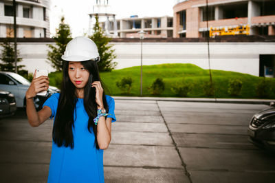 Young woman wearing hardhat while taking selfie on road