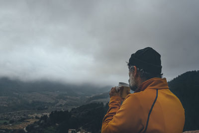 Rear view of man looking at cityscape against sky