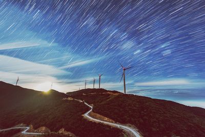 Low angle view of windmills on landscape against sky