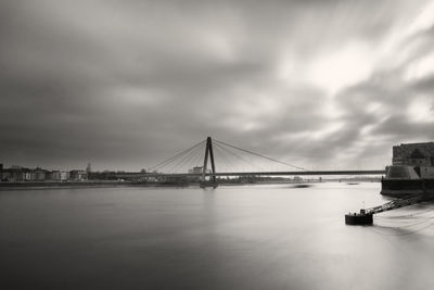 View of suspension bridge over sea against cloudy sky