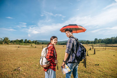 Friends standing on field against sky