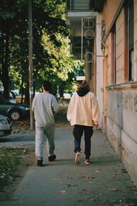 Rear view of men walking on street in city