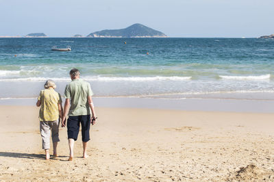 Rear view of people at beach against sky