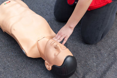 Midsection of paramedic practicing on cpr dummy at blanket