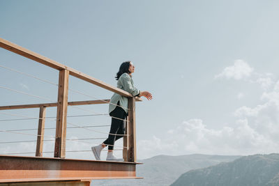 Low angle view of bird perching on railing against sky