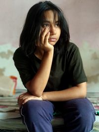 Portrait of young woman sitting on chair at home