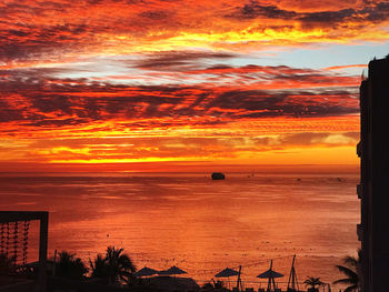 Scenic view of sea against dramatic sky during sunset