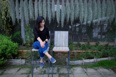 Young woman sitting on plant against trees