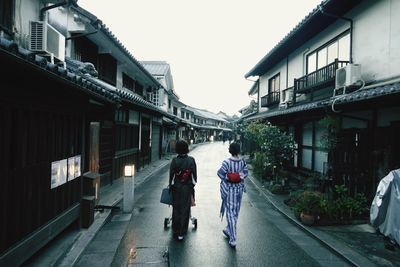 Rear view of people walking on street amidst buildings