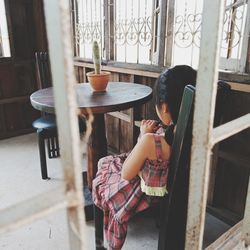 Woman sitting on table by window