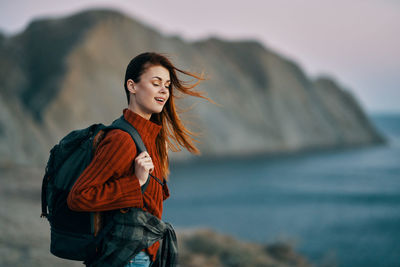 Young woman looking away while standing on sea shore