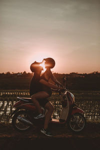 Side view of man sitting bicycle against sky during sunset